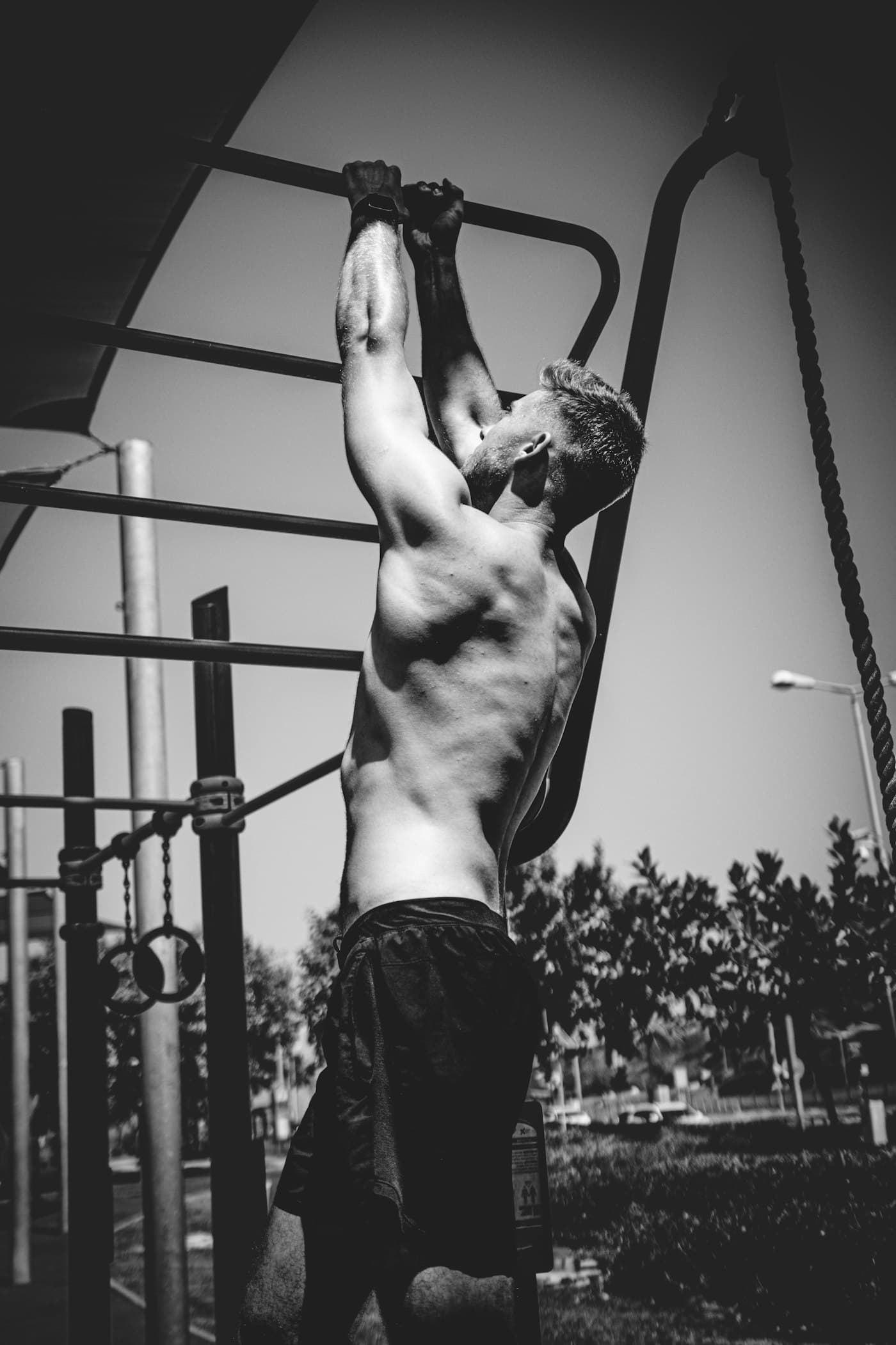 Athlete in black and white pulling up on an outdoor bar